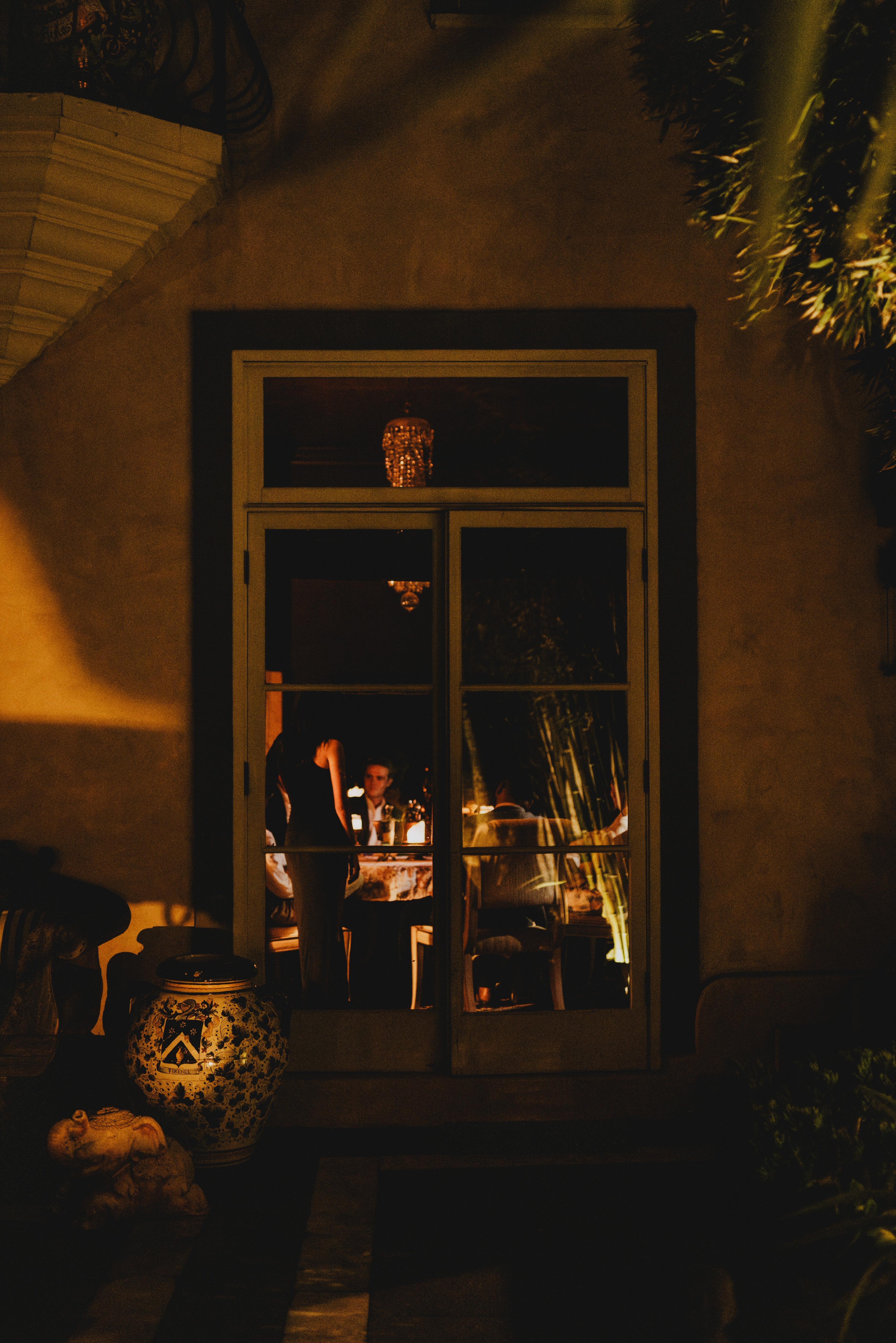 A glimpse through warmly lit doors at an evening gathering