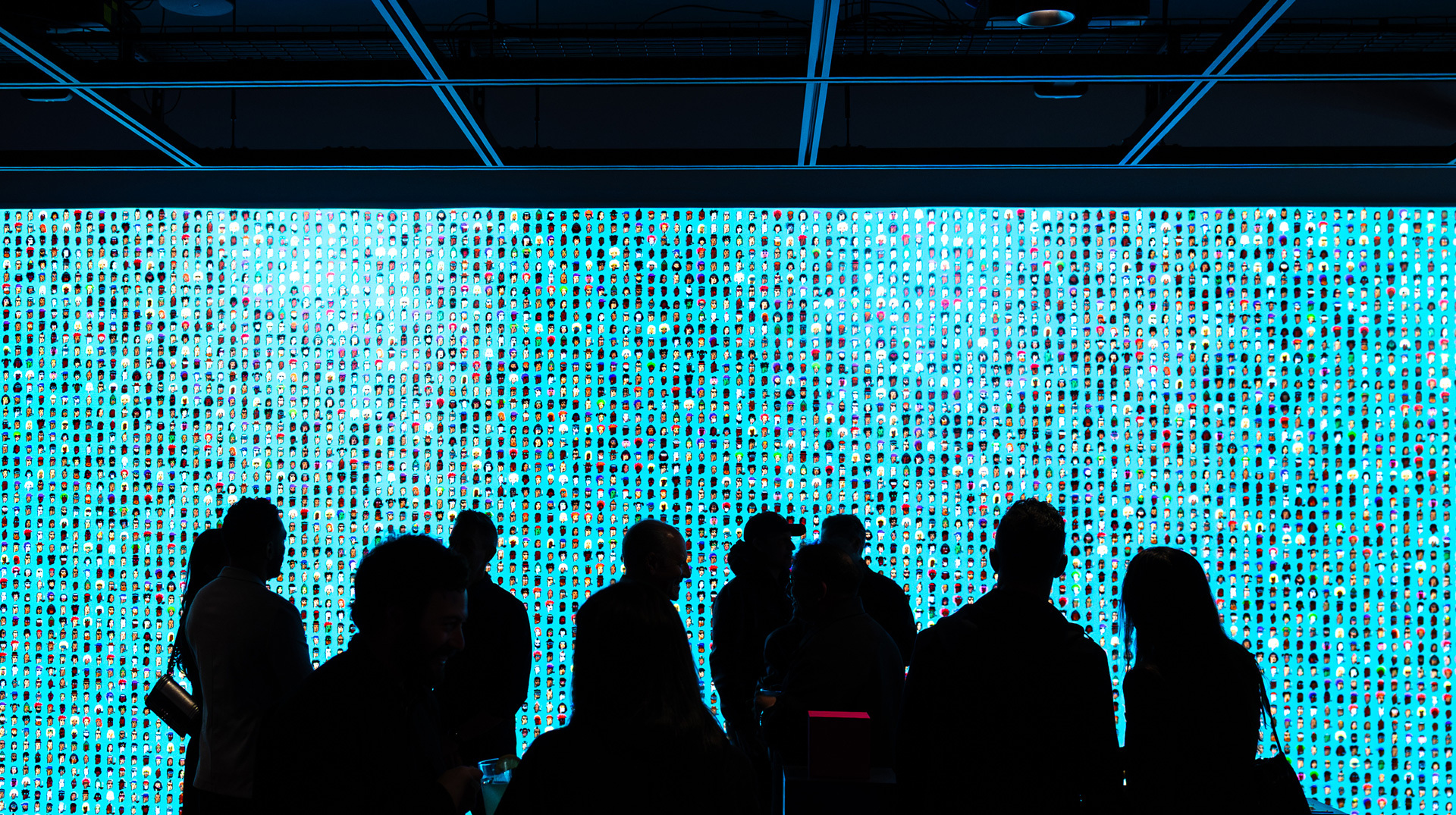 Guests in conversation in front of a blue illuminated art wall